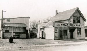 Woollatt's original building from the late 1950s. Photo depicts a small two storey building with the sign "Woollatt Fuel & Lumber" as well as a second building on the left behind the main building.